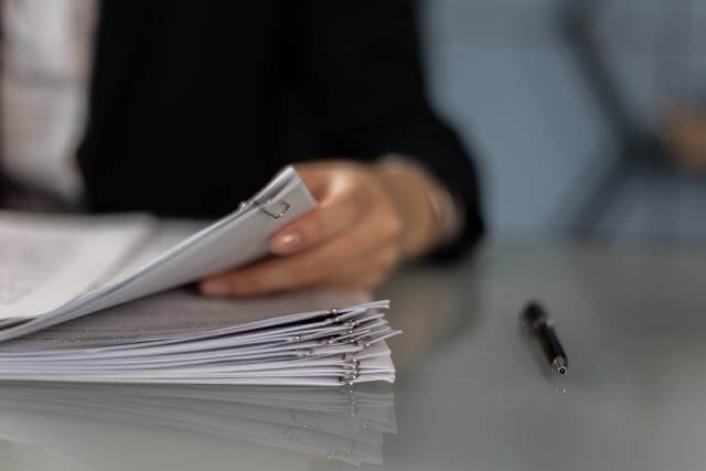 Edificio de tribunal federal con documentos legales apilados que representan el costo de una demanda de mandamus